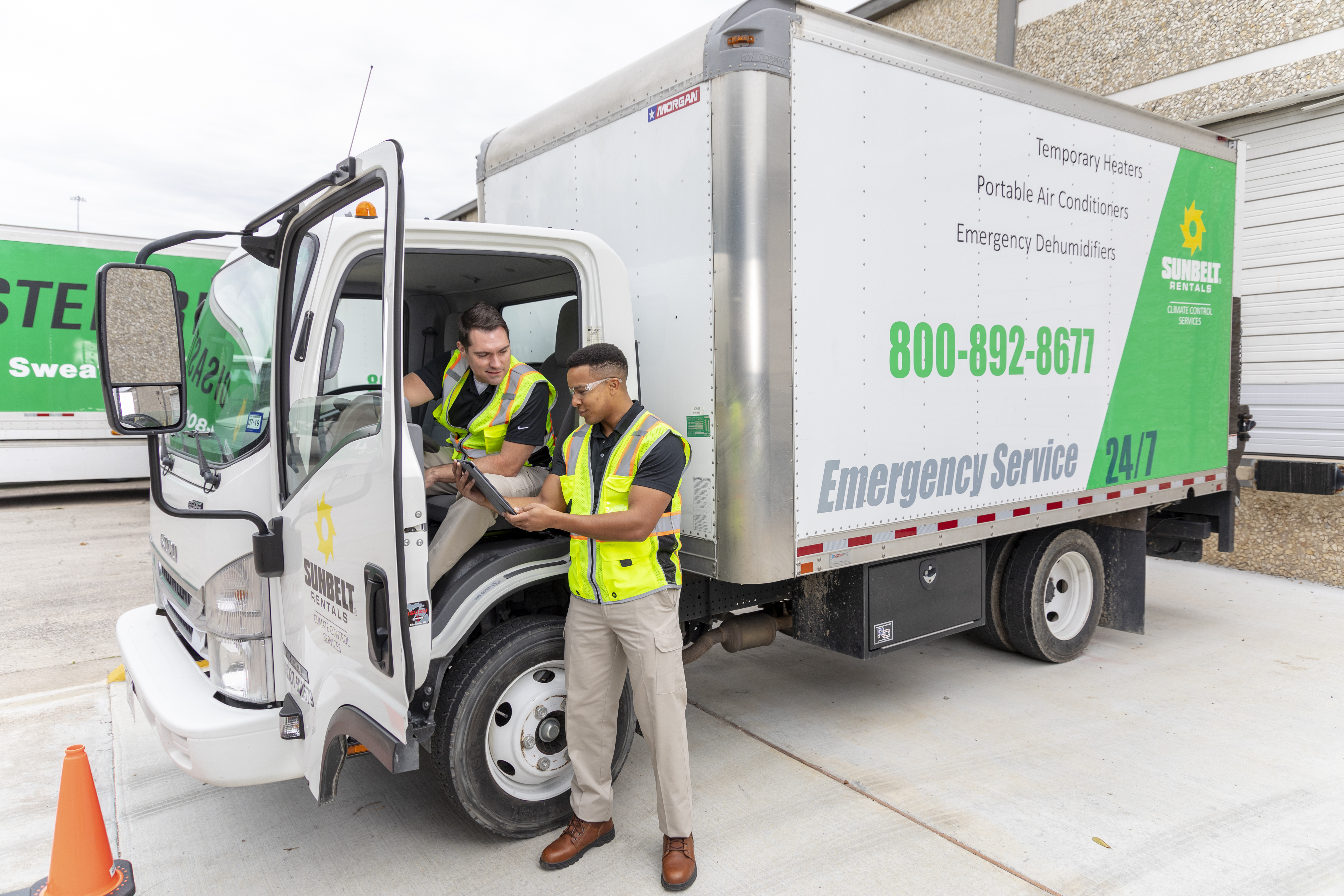 Two employees at a Sunbelt Rentals Emergency Service Truck review information on a tablet device.