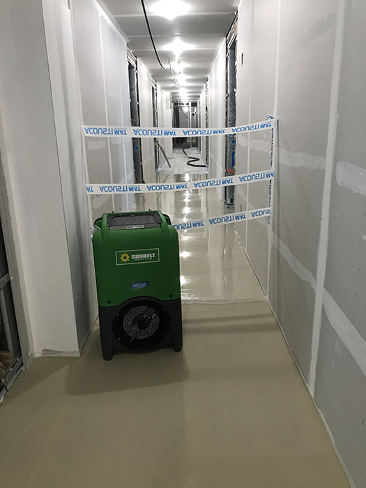 A dehumidifier in the hallway of a building that is under construction.